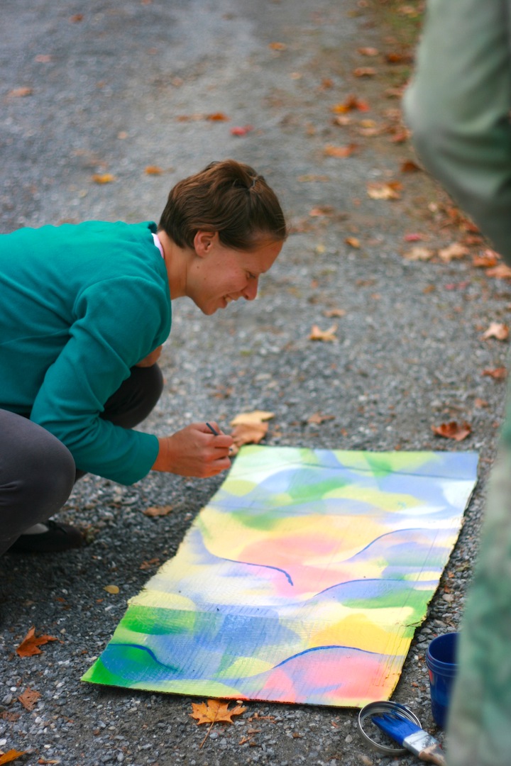 The women with short hair and green top paints in cardboard with spray paint.