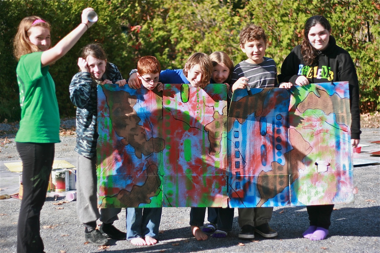 Children show their graffiti art holding it up infrint of their bodies .