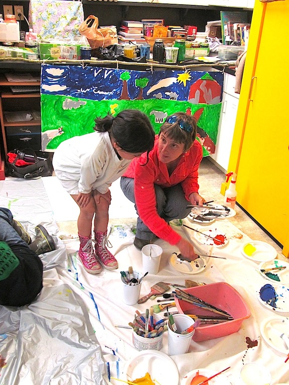 Jean and a child looking at a painting on the ground 