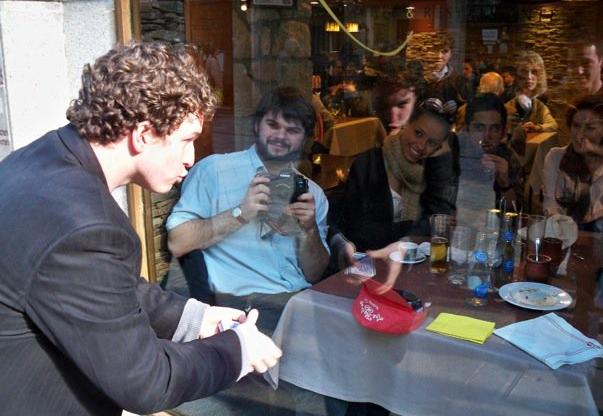 Evan performs a card trick through a glass window for restaurant diners