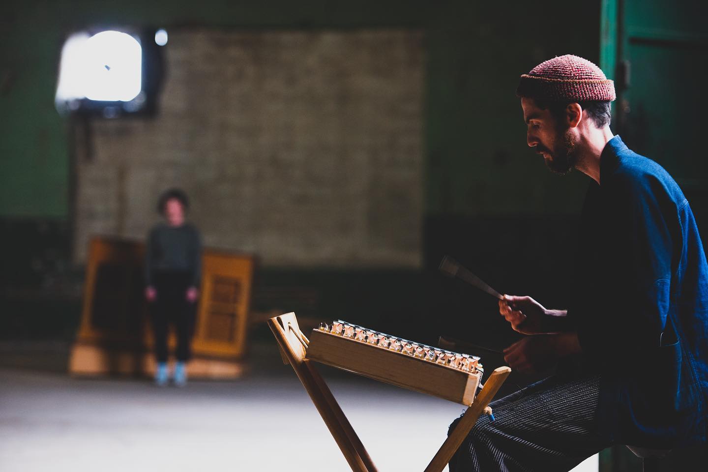 dancer Taryn is standing next to a piano in the background while musician Cole plays the hammered dulcimer