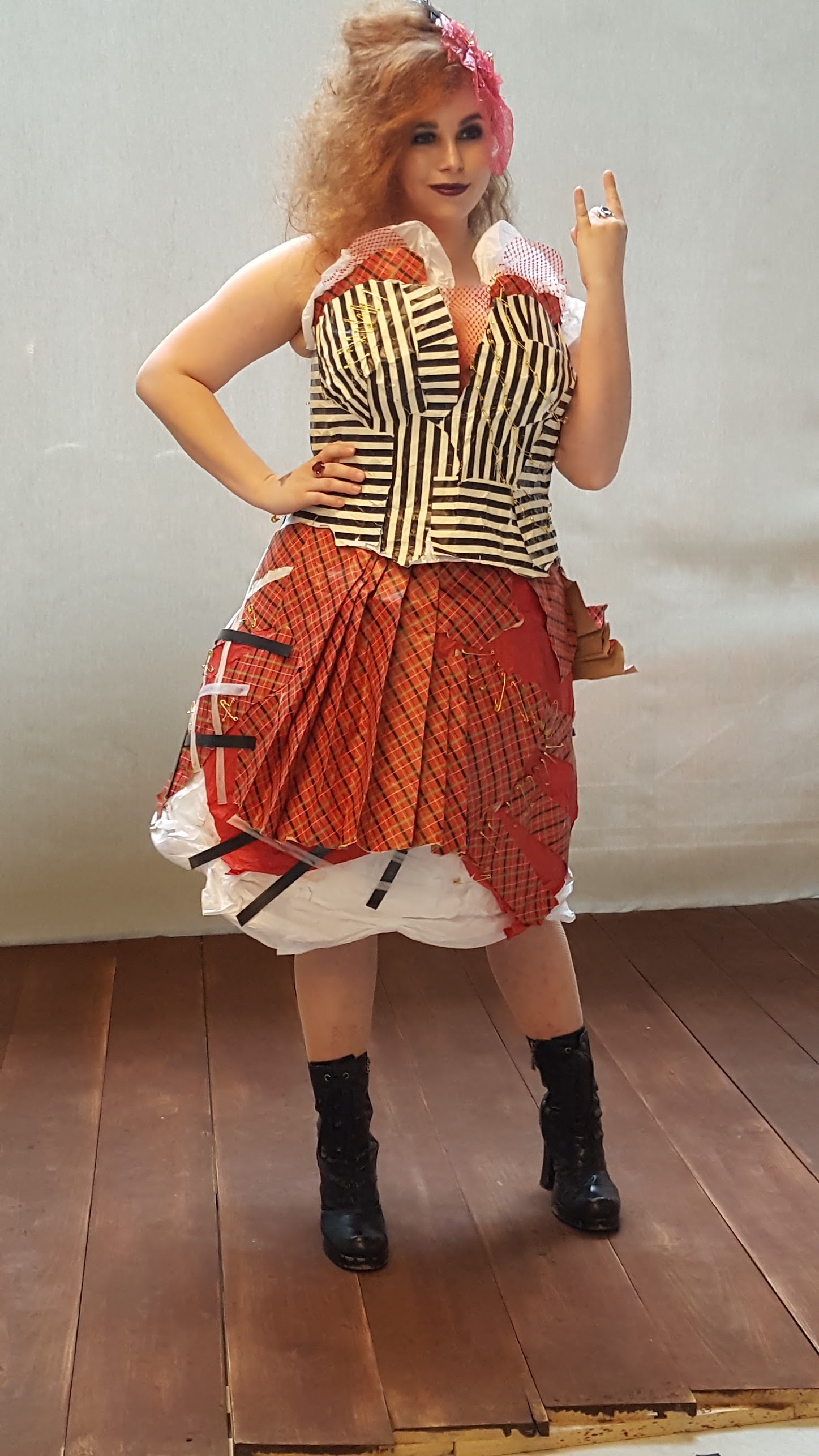 A woman wearing a punk inspired outfit that is made of red, white and black striped wrapping paper.