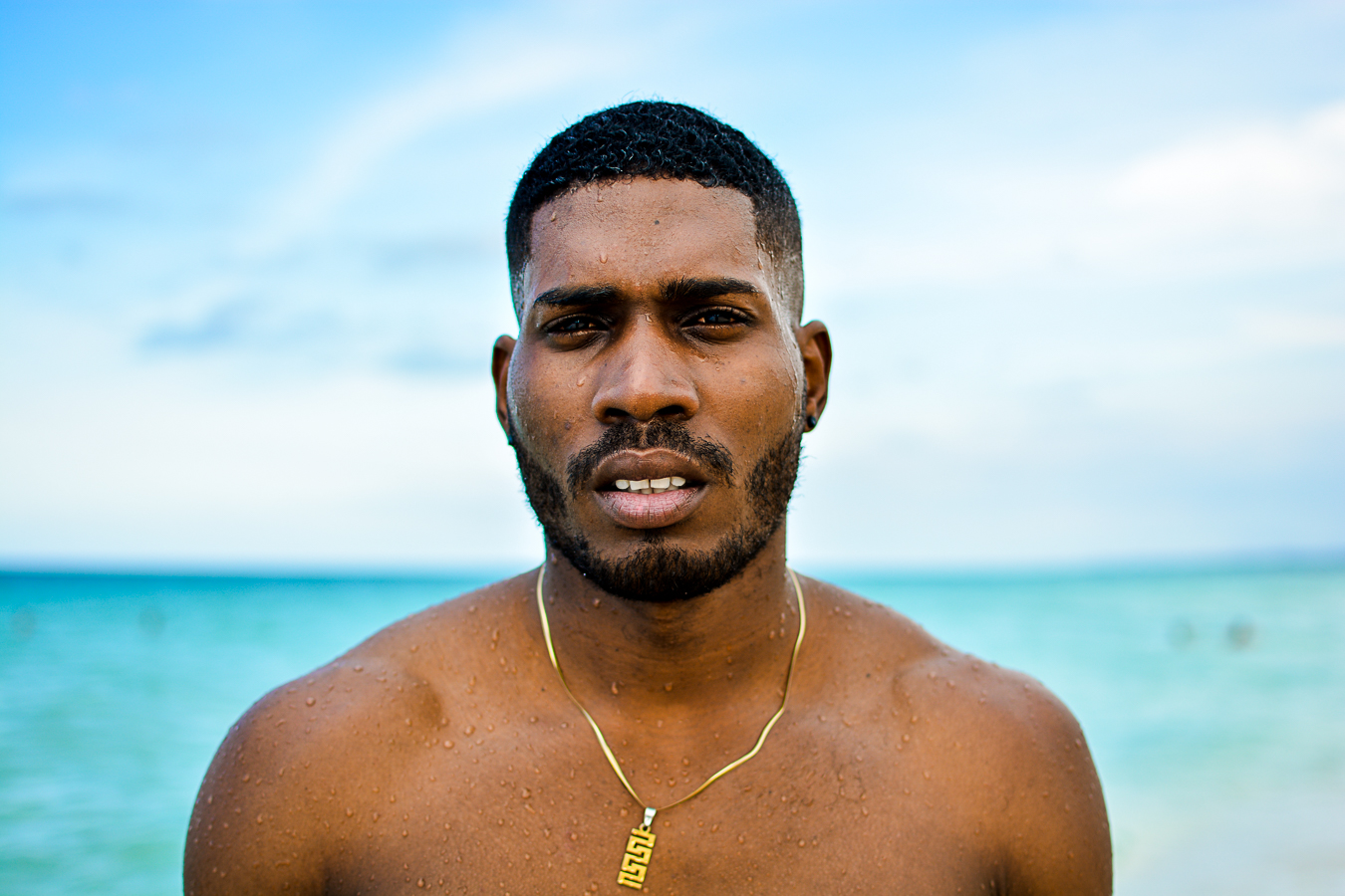 Headshot of a Black man with ocean and sky background.