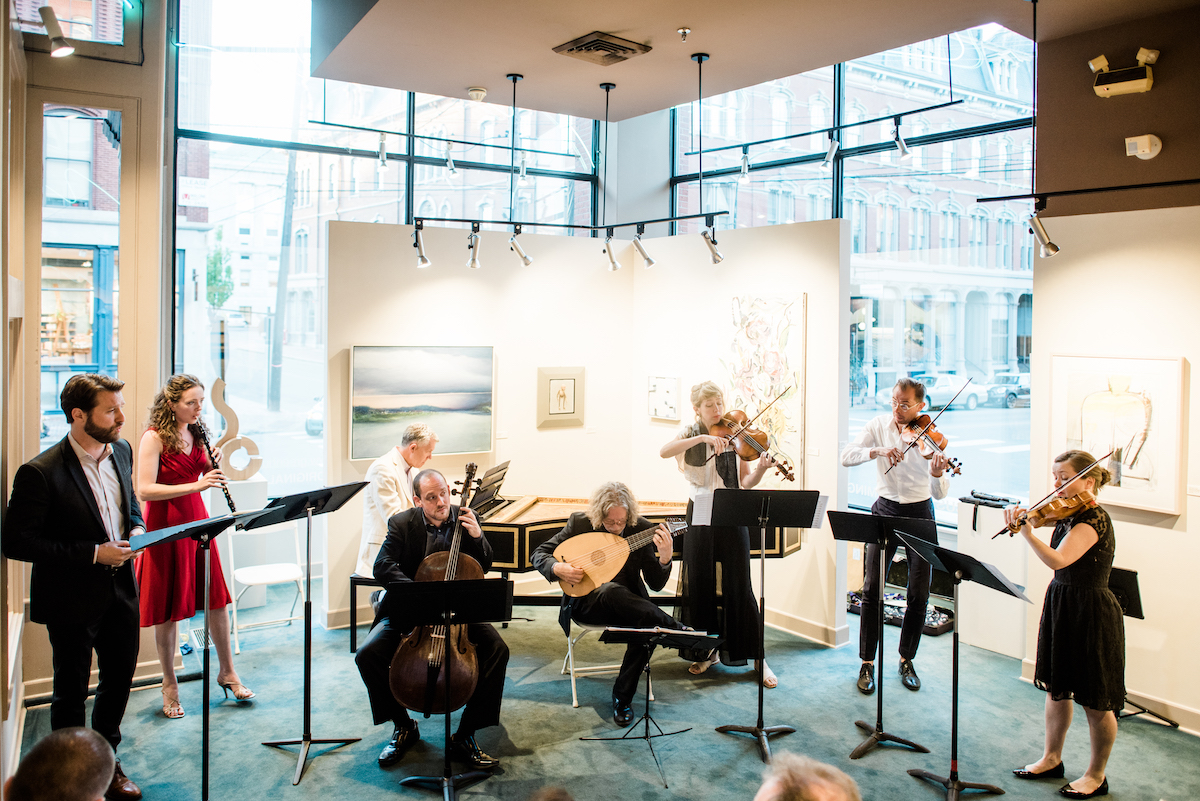 chamber orchestra with string instruments, harpsichord, and oboe in an art gallery