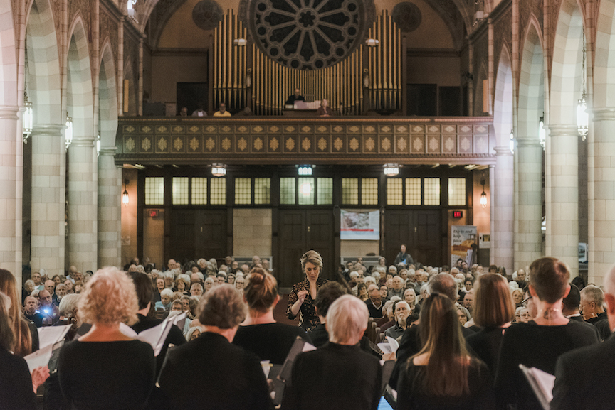 View from behind choir looking at conductor and audience