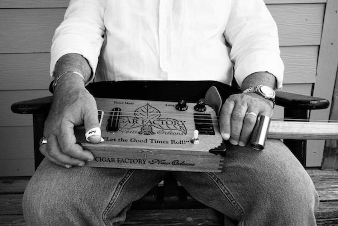 David Reed's hands resting upon a cigar box guitar