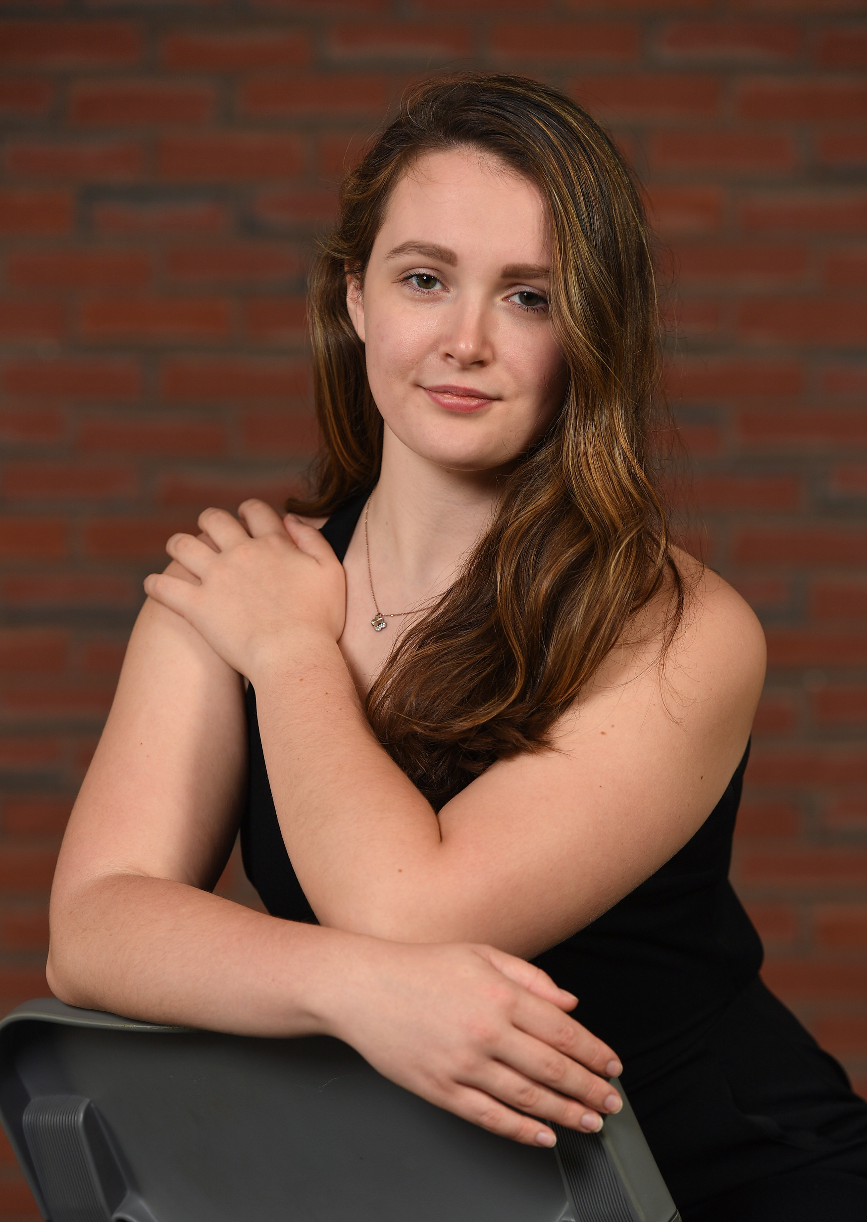Dancer sitting on chair, smirking, hand on shoulder