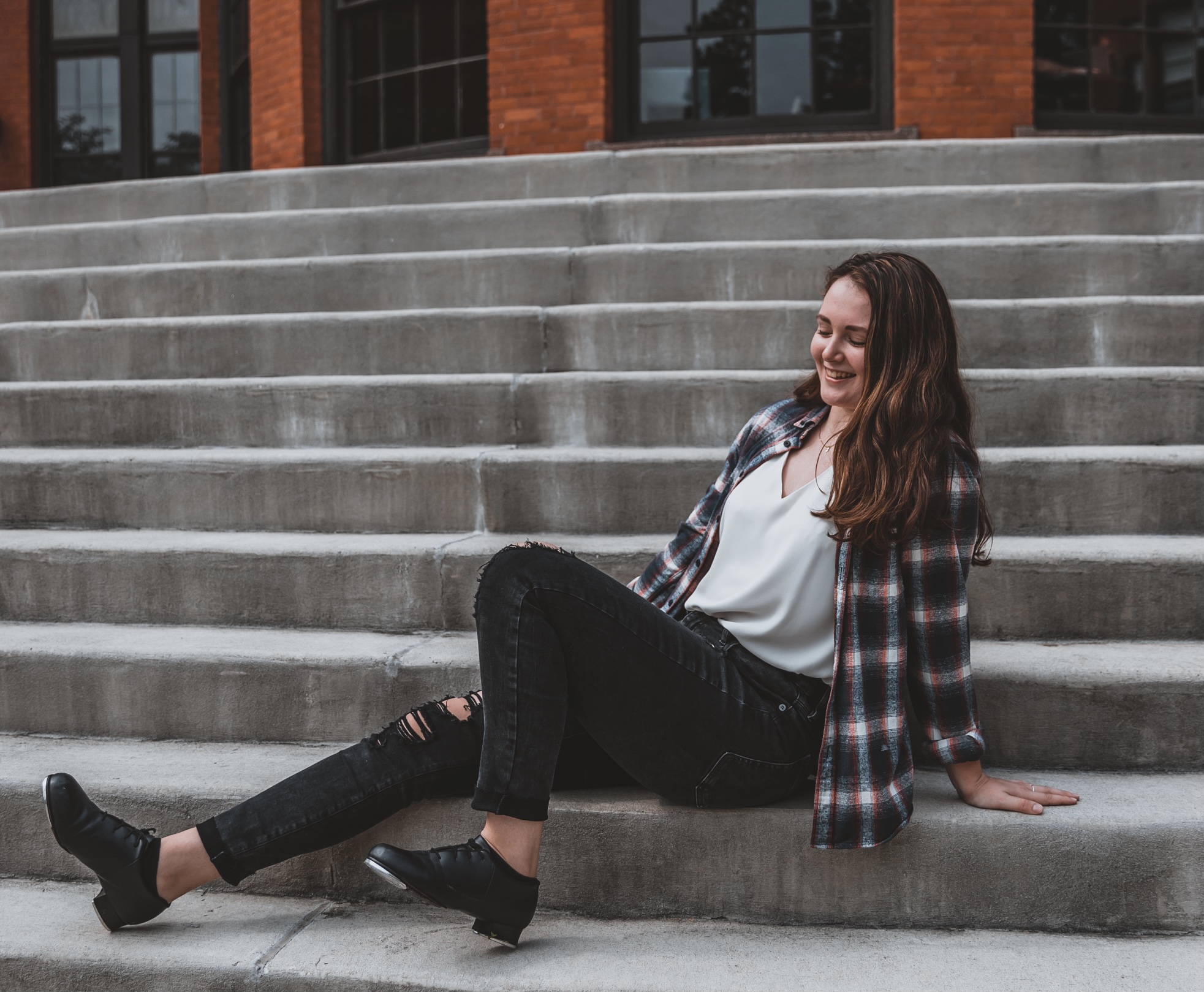 Dancer smiling wearing tap shoes sitting on stairs
