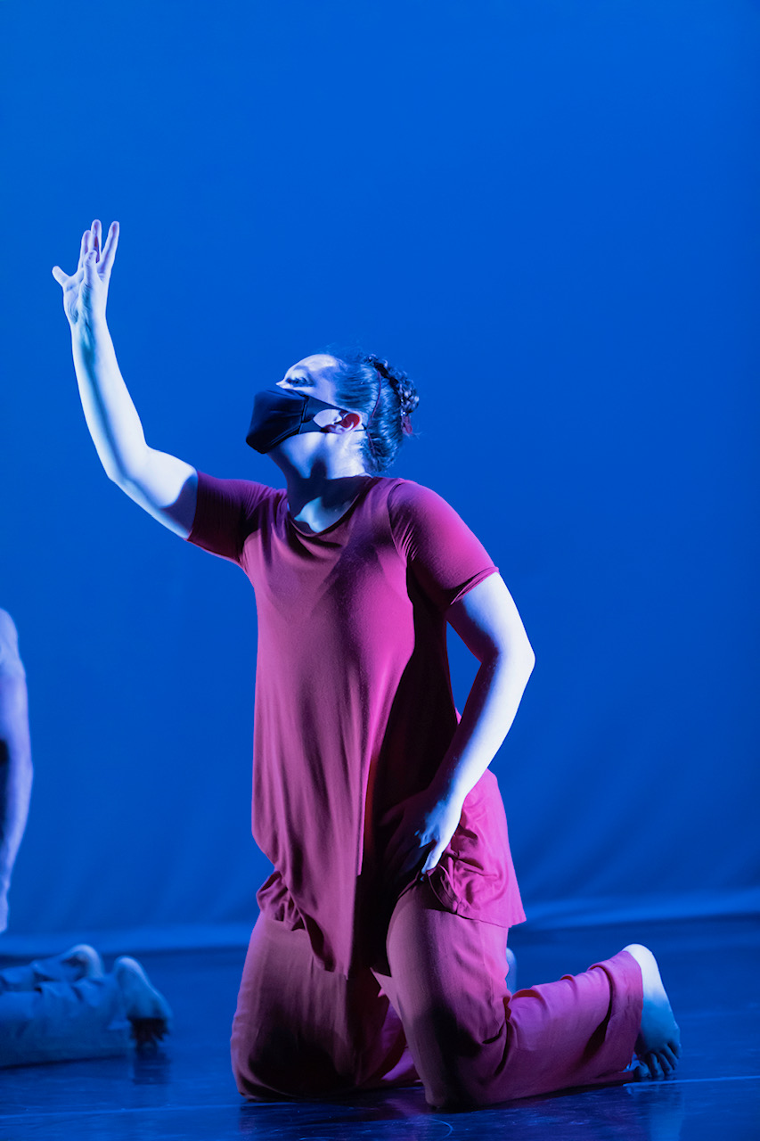 Dancer in mask and rust costume reaching up
