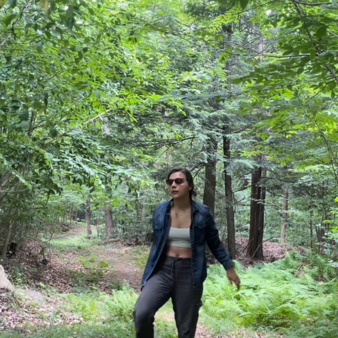 Dana Duren stands in a forest with leg bent and one arm slightly outstretched, as I’d anticipating a movement. 
