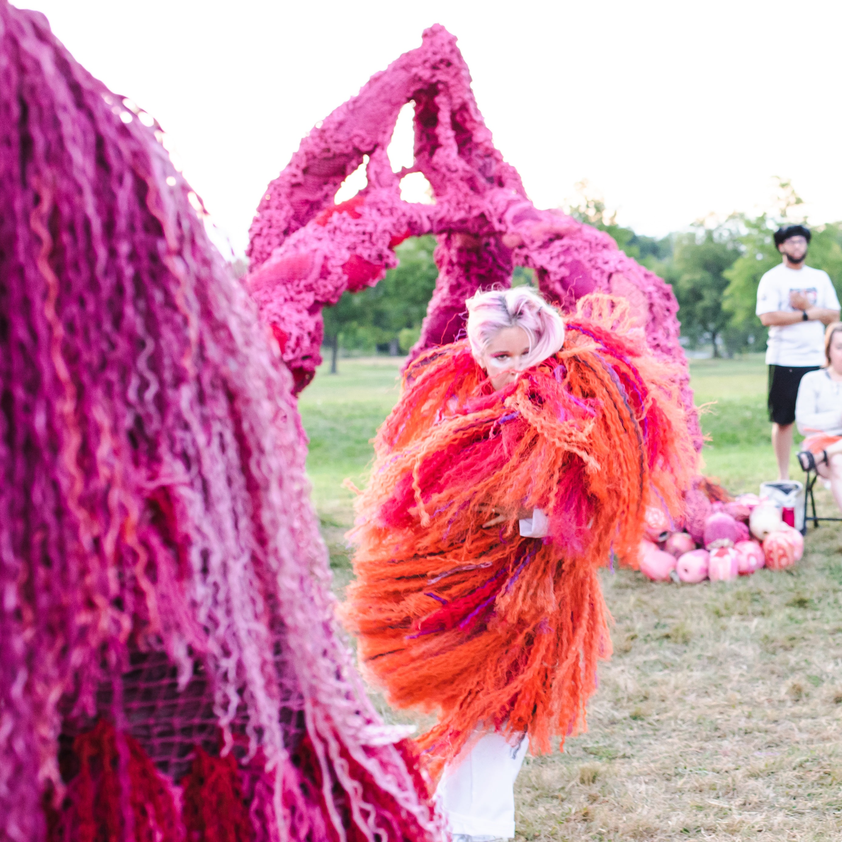 Hannah dances with orange rope shawl amongst pink public art scultures