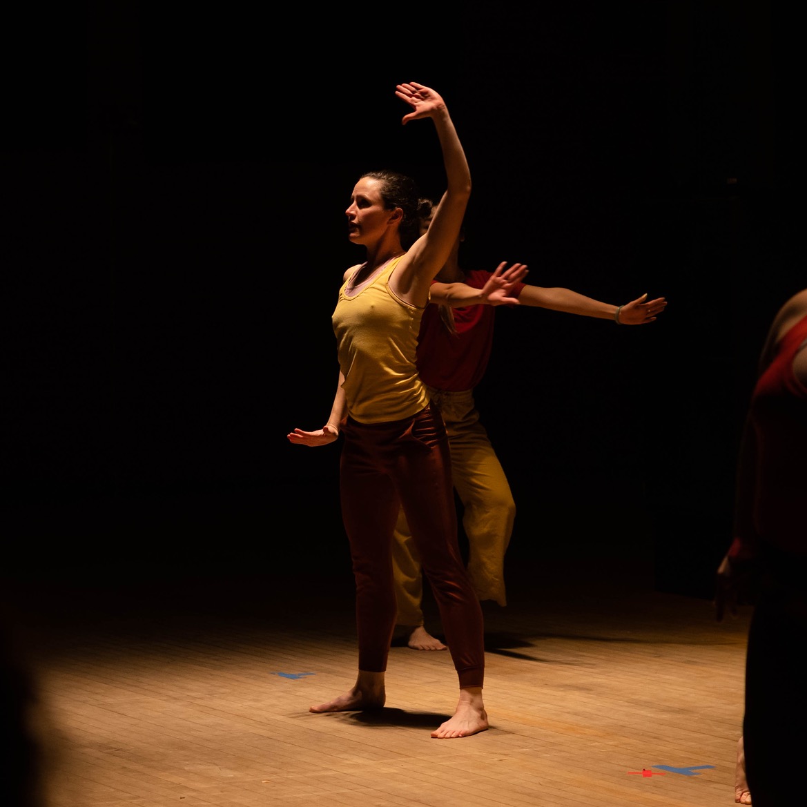 Woman standing with her chest open, one arm reaching towards the ceiling, palm turned out