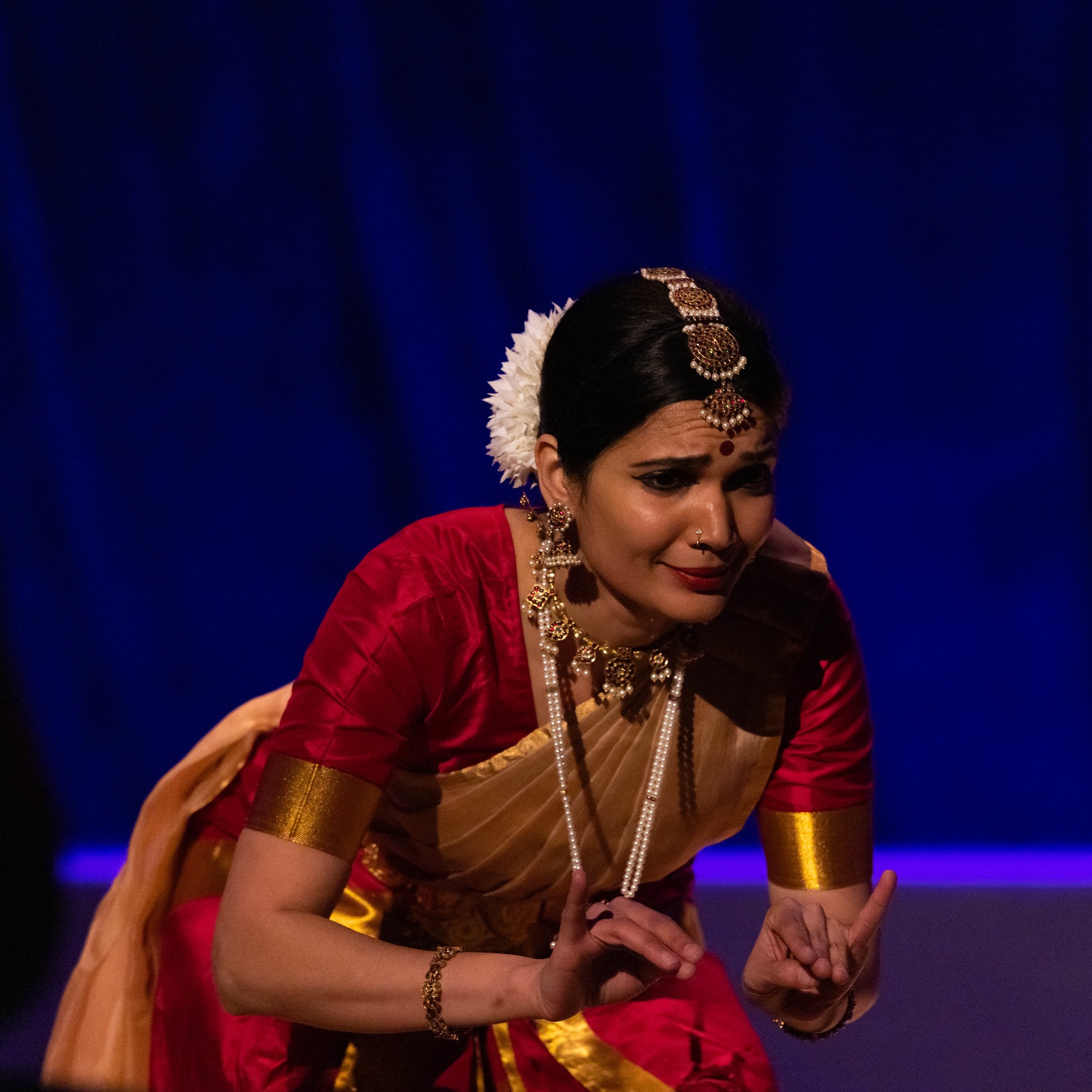 Dance artists Soumya Rajaram in classical Indian dress leaning forward as though sharing a secret with the audience