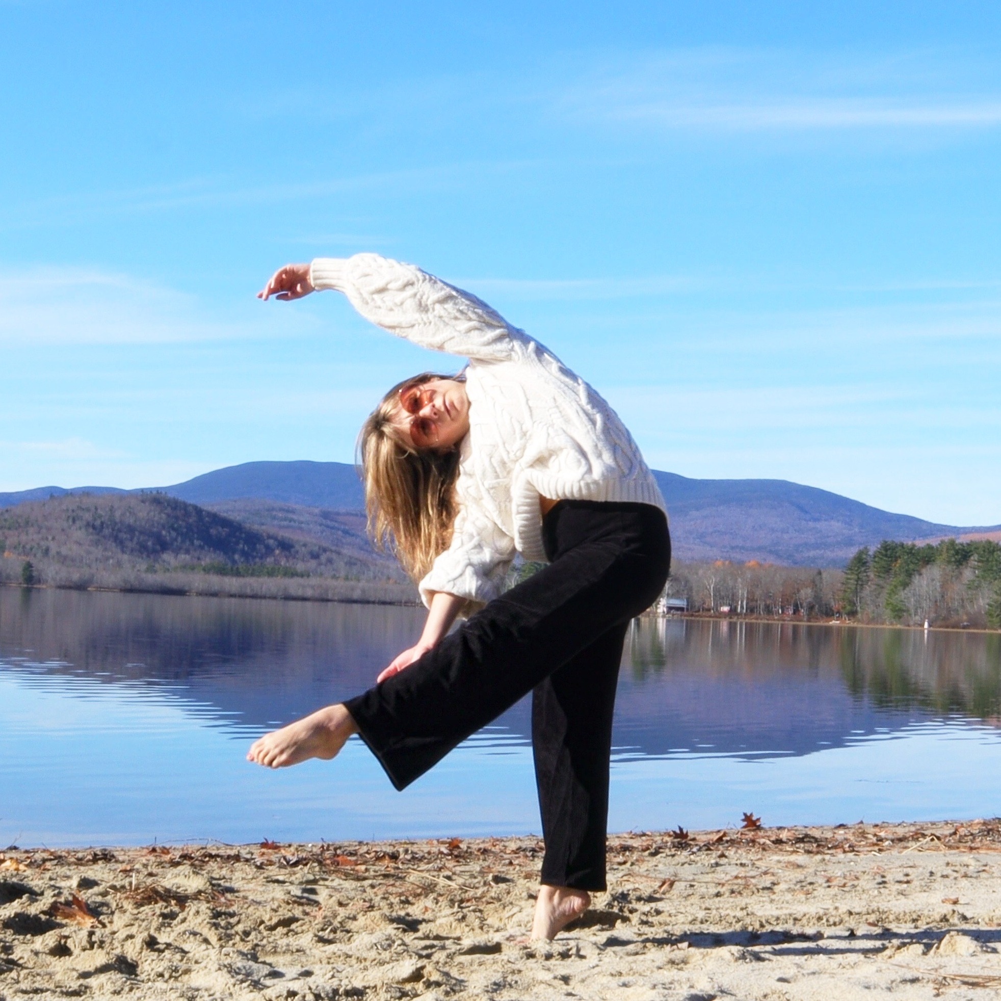 With her upper body in a full curve to the right side, with the arm rounding over head, Christina's left leg crosses her supprtoing leg on a low diagonal on a mountainous lake front.