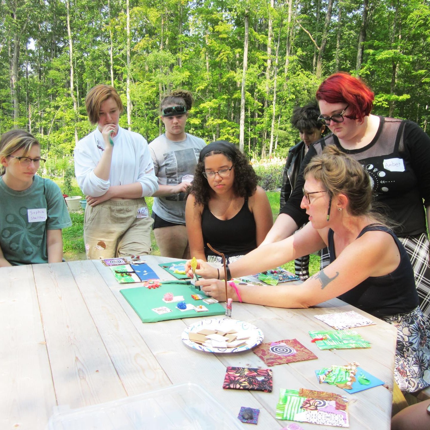 Teaching Artist Meghan Samson explaining an art project surrounded by a group of teenagers