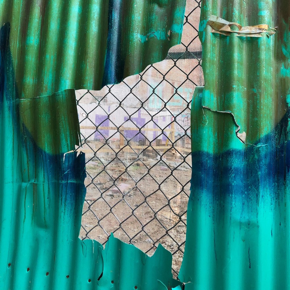 An abstract image peaking through a wire fence to a construction site