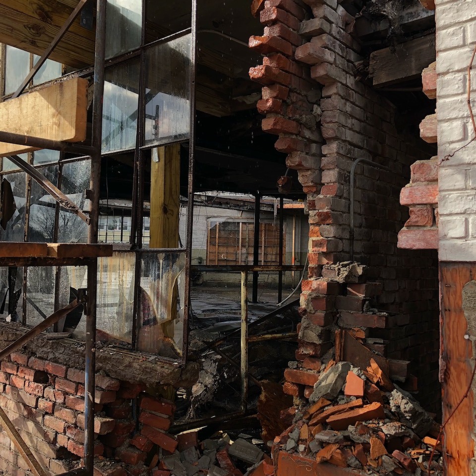 An image of a brick wall and windows in the process of being demolished