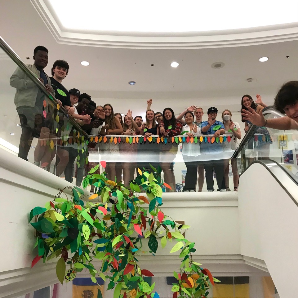 A group of students behind an art project they made of a tree canopy.