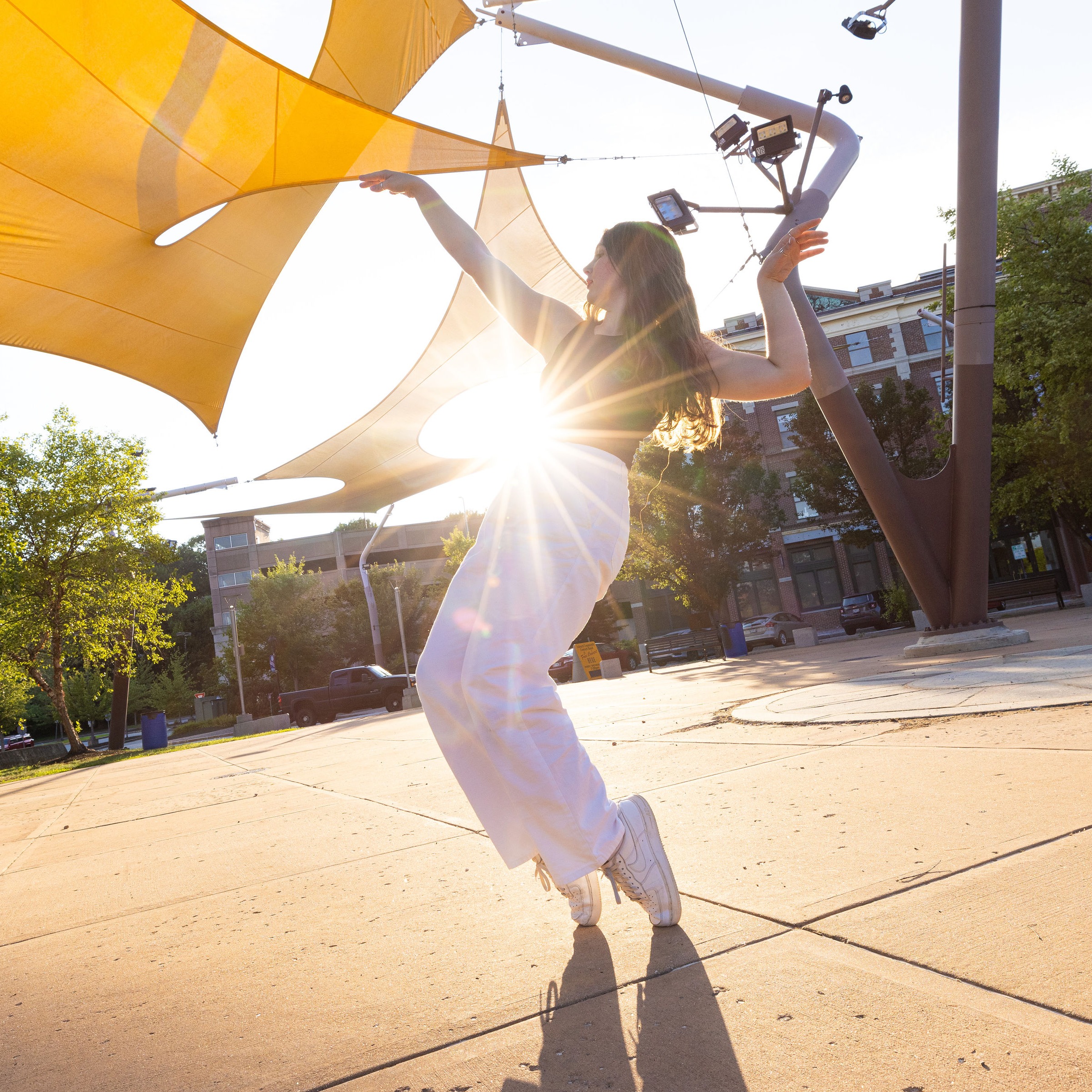 Dancer in the sunshine wearing a black tank top and white pants standing on her toes