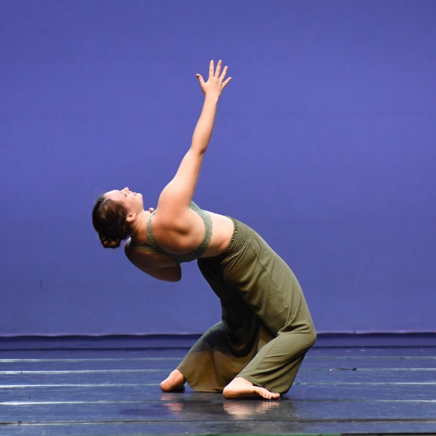 Dancer in olive green in a hinge reaching up