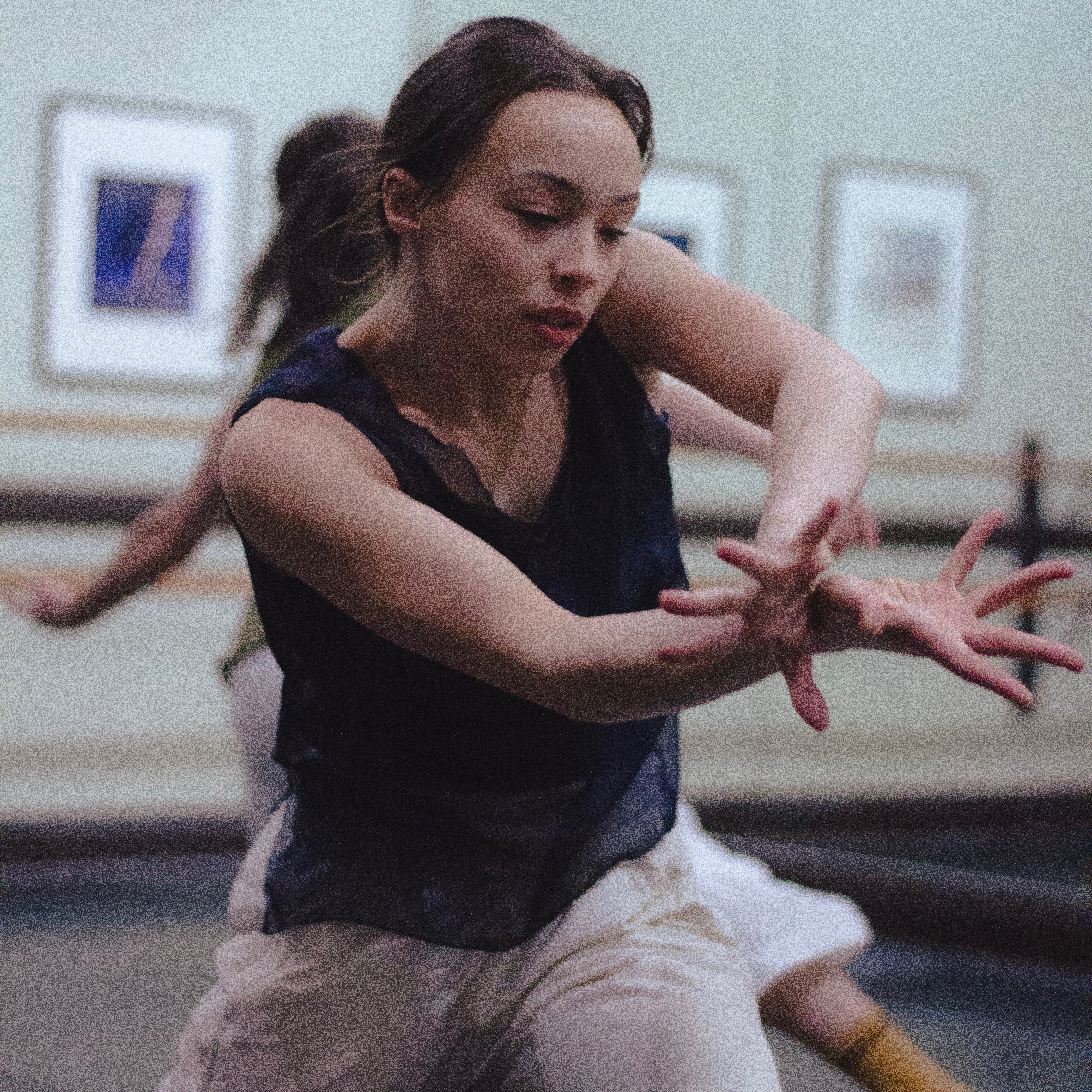 Dancer in lunge, wrists crossed in front with fingers splayed