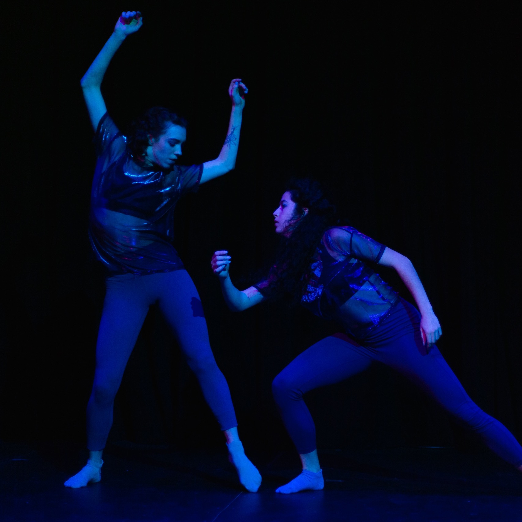 Two women bathed in blue light with limbs bent at many angles