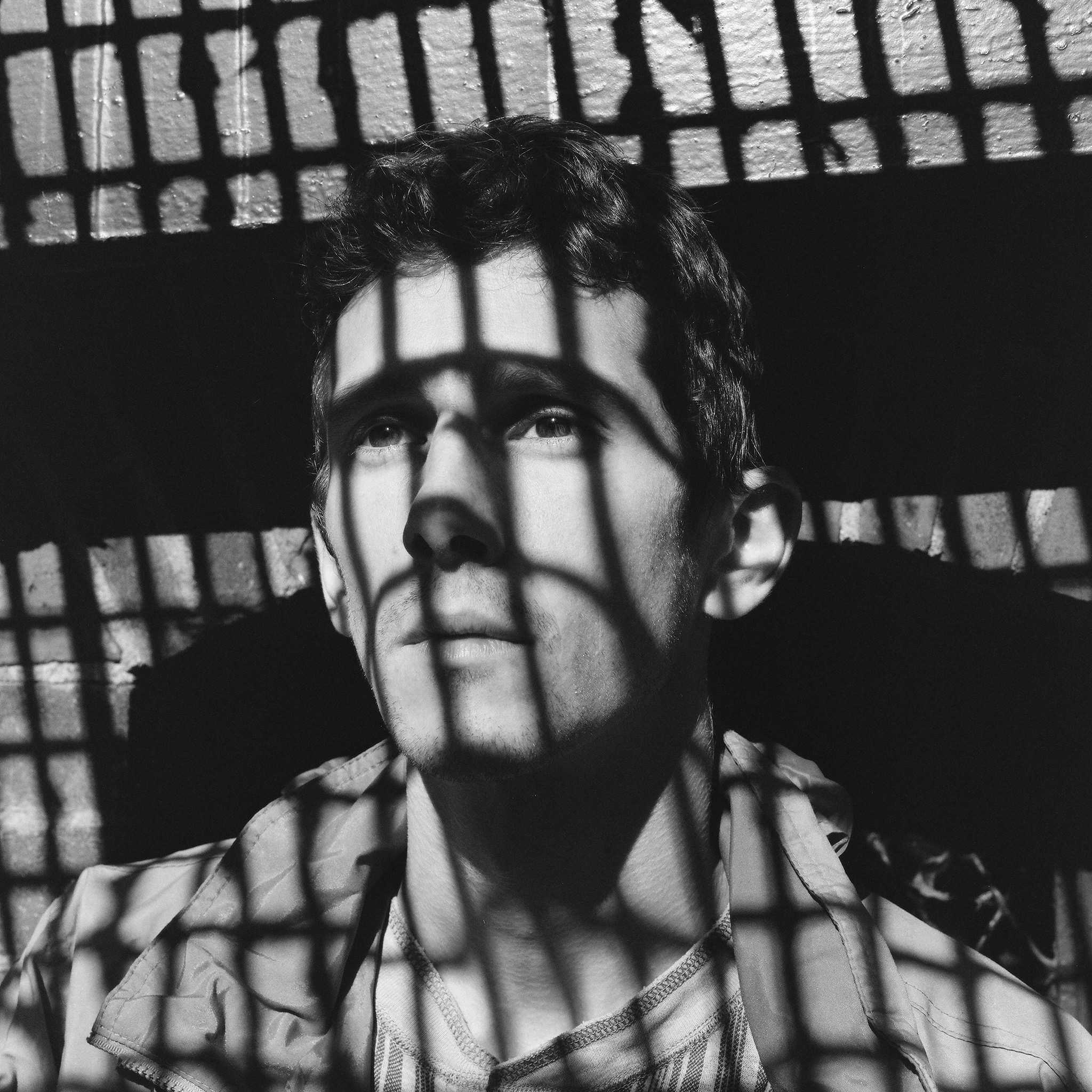 The artist in black and white, silhouetted by a metal grate