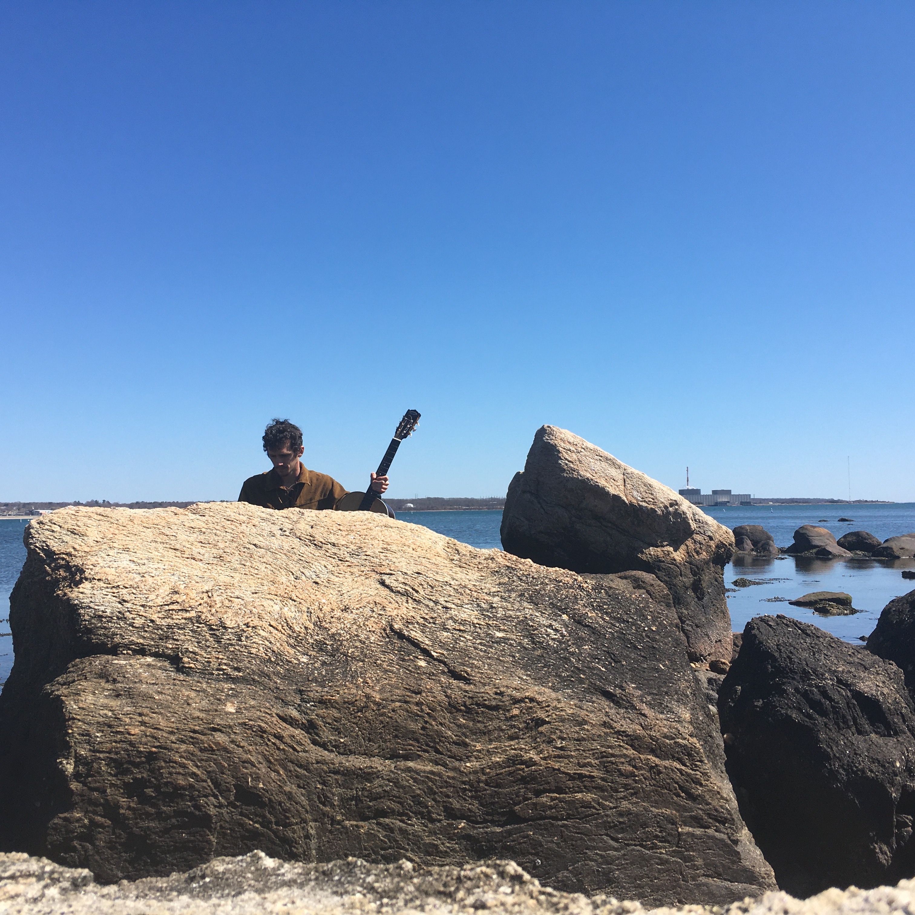 The artist, obscured by a large boulder on a beach in Connecticut