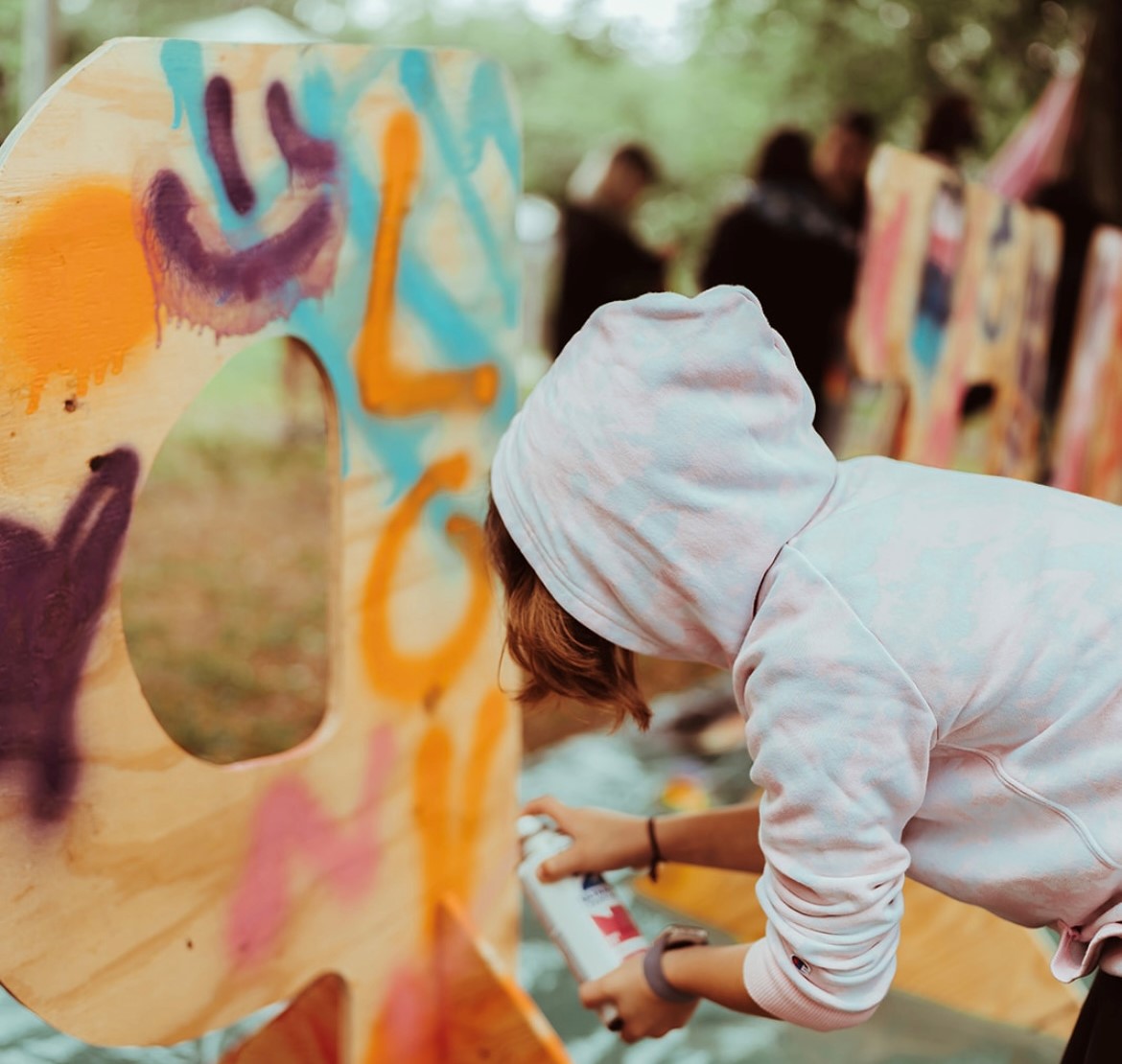 Child spray painting wood letter during an interactive art activity 