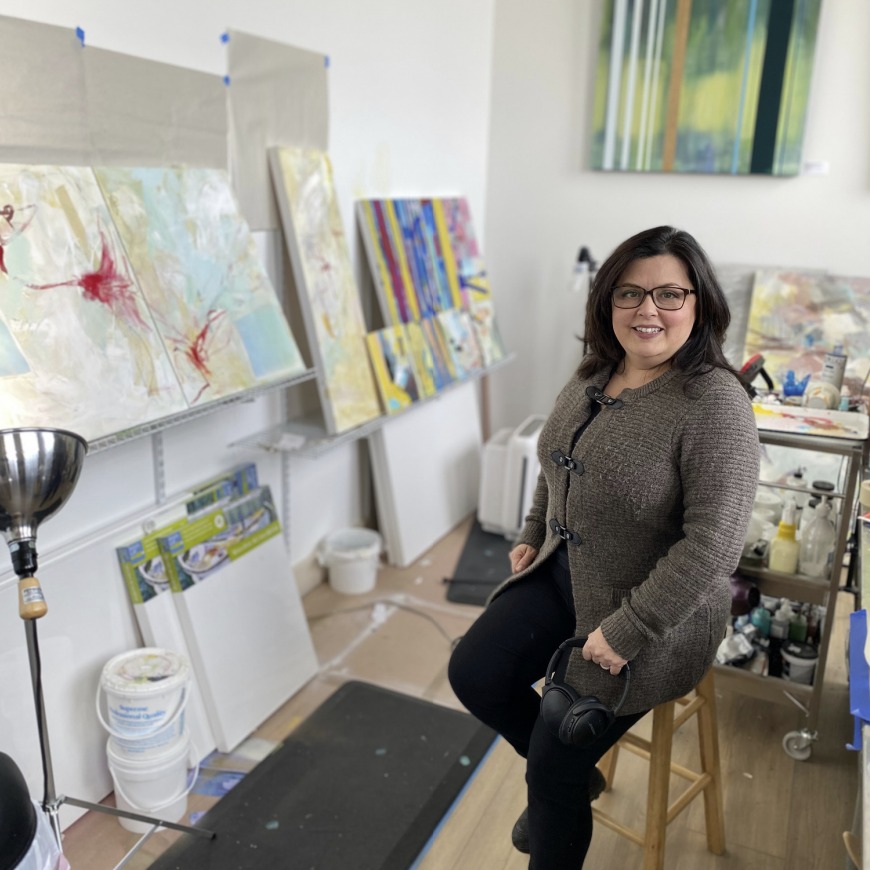 Shany Porras Art - Artist holding headphones in her painting studio