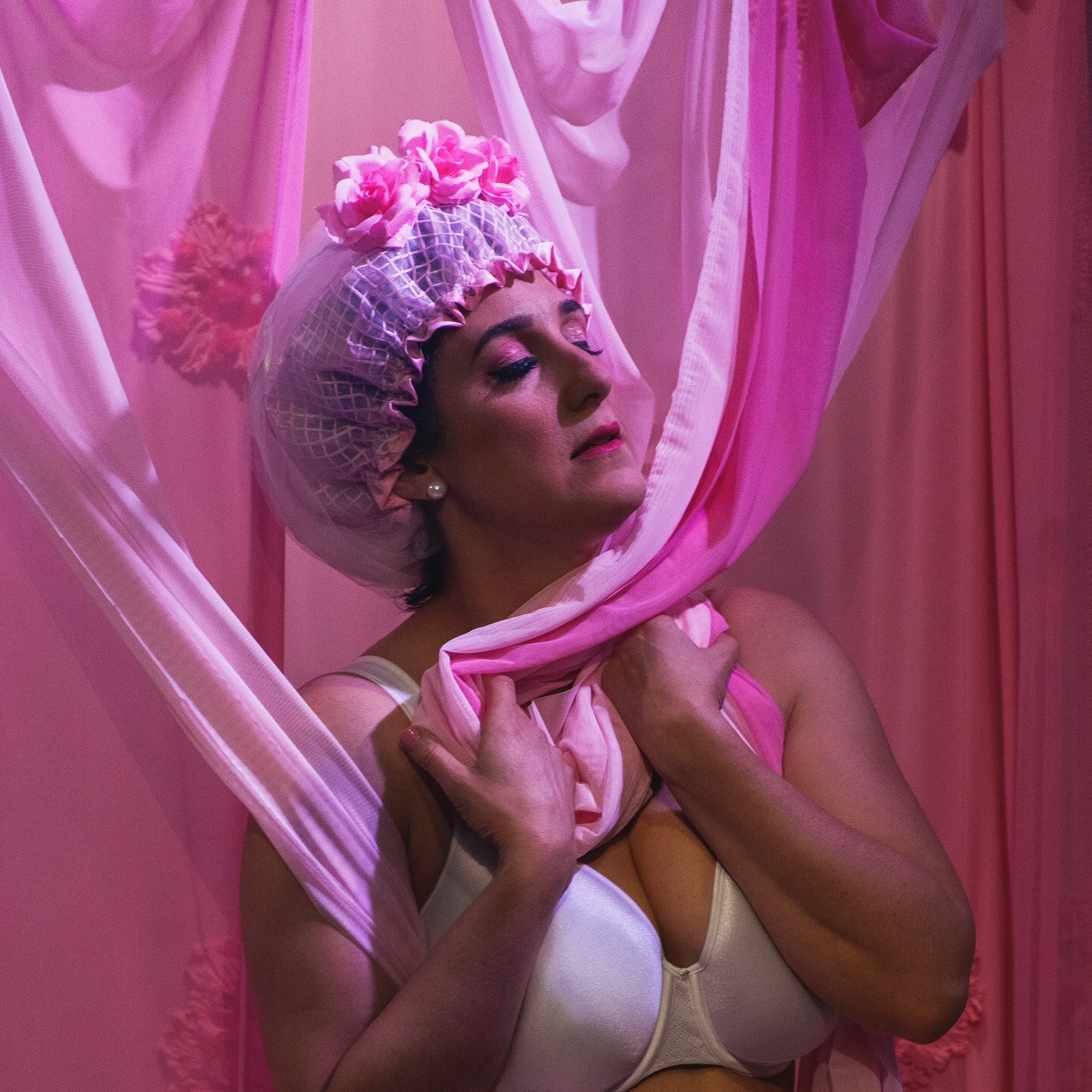 female wearing pink shower cap with flowers standing in an abstract shower