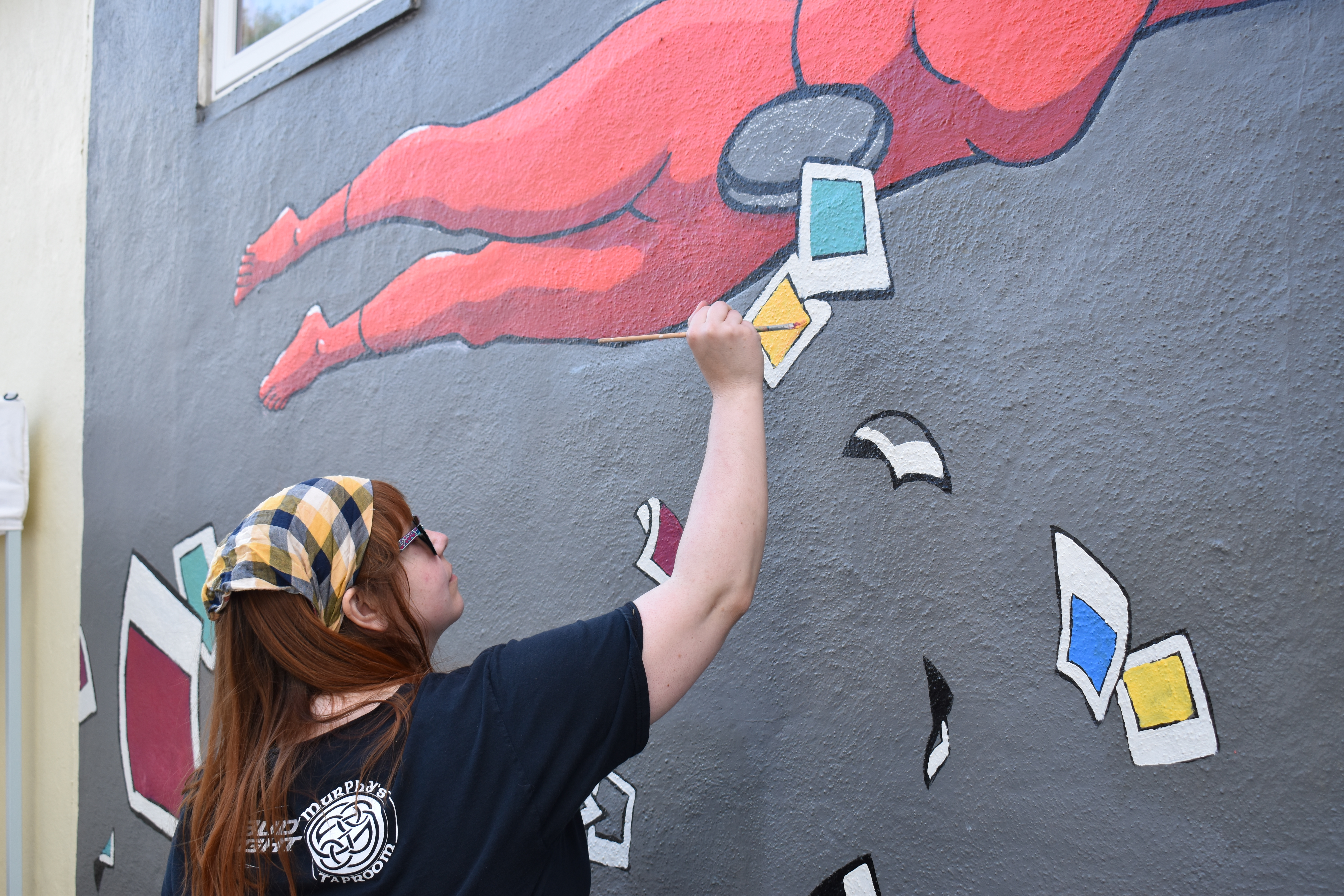 Director Laura Harper Lake paints a Creative Guts-inspired mural on the side of Art Up Front Street Studios and Gallery in Exeter.