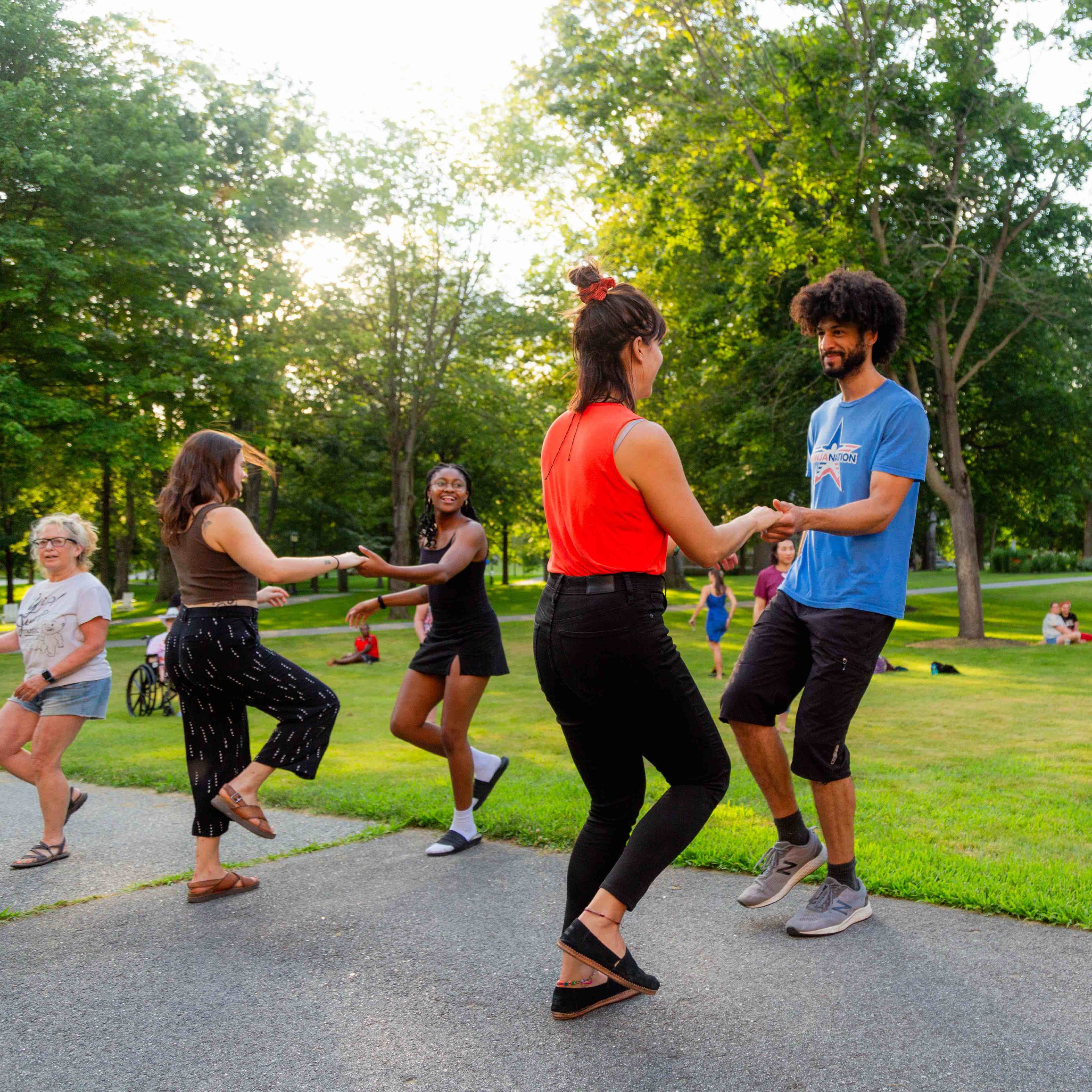 A group of people dance together outside.