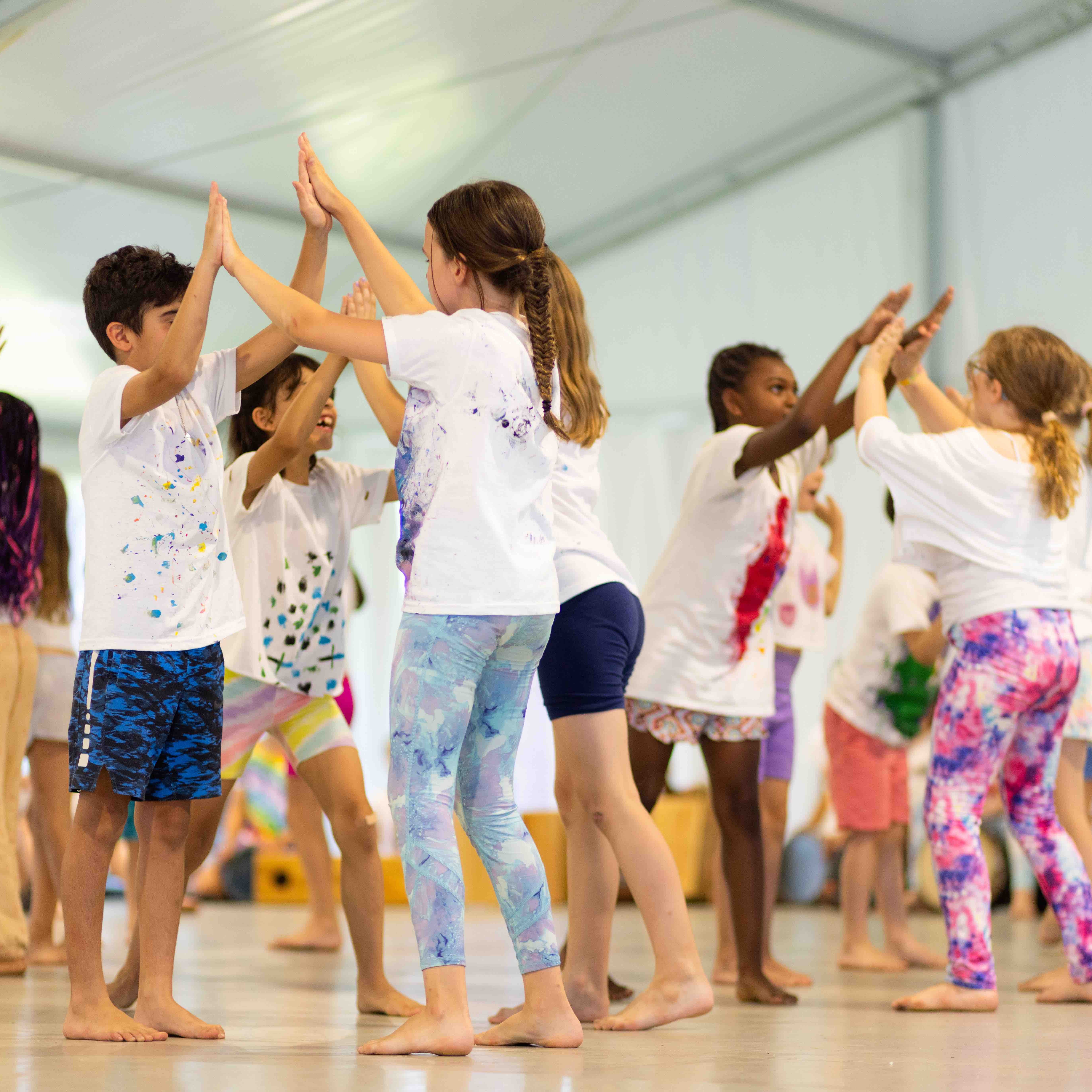 A group of young students perform a dance together on a stage.