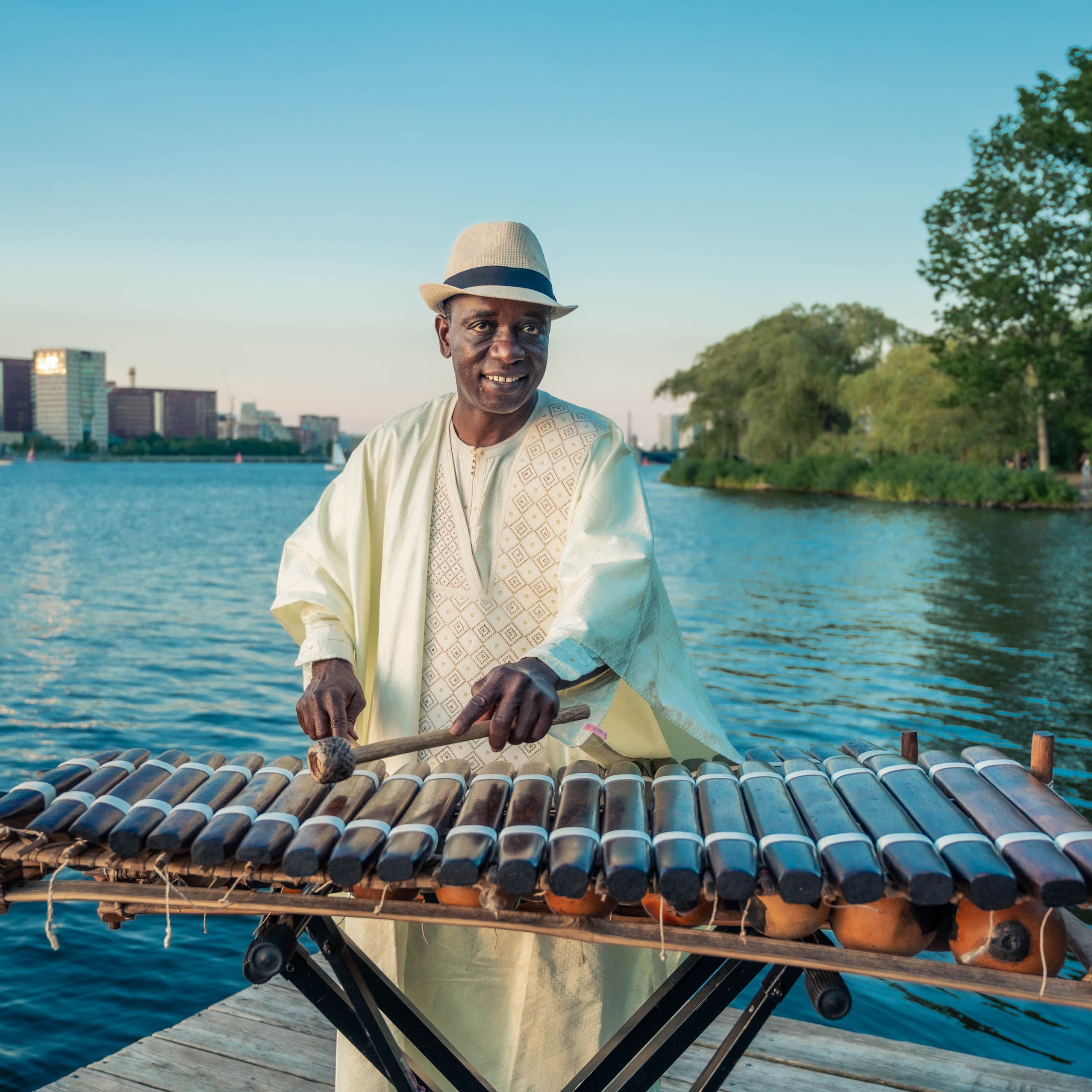 Balla Kouyate poses with his balafon on a dock on the Charles River in Boston, MA