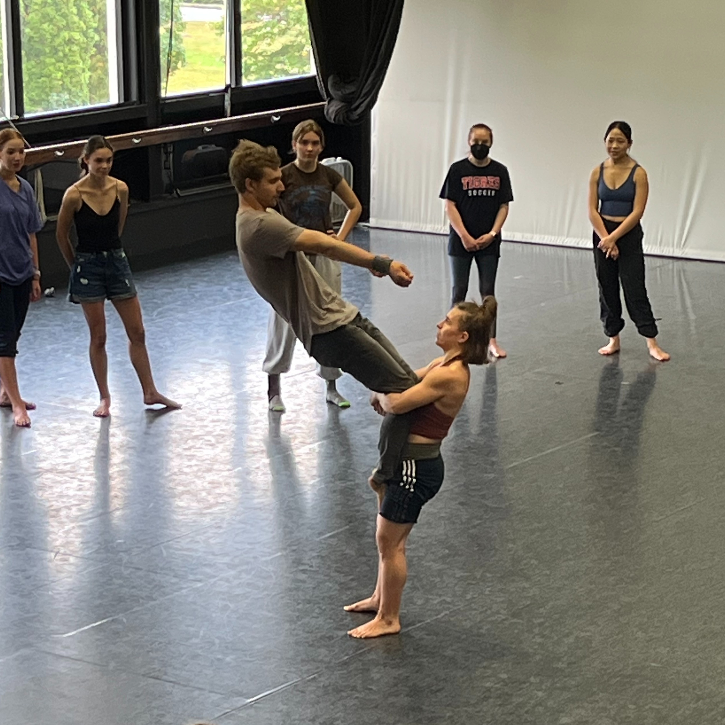 Female circus performer demonstrates a lift of a male performer in workshop.