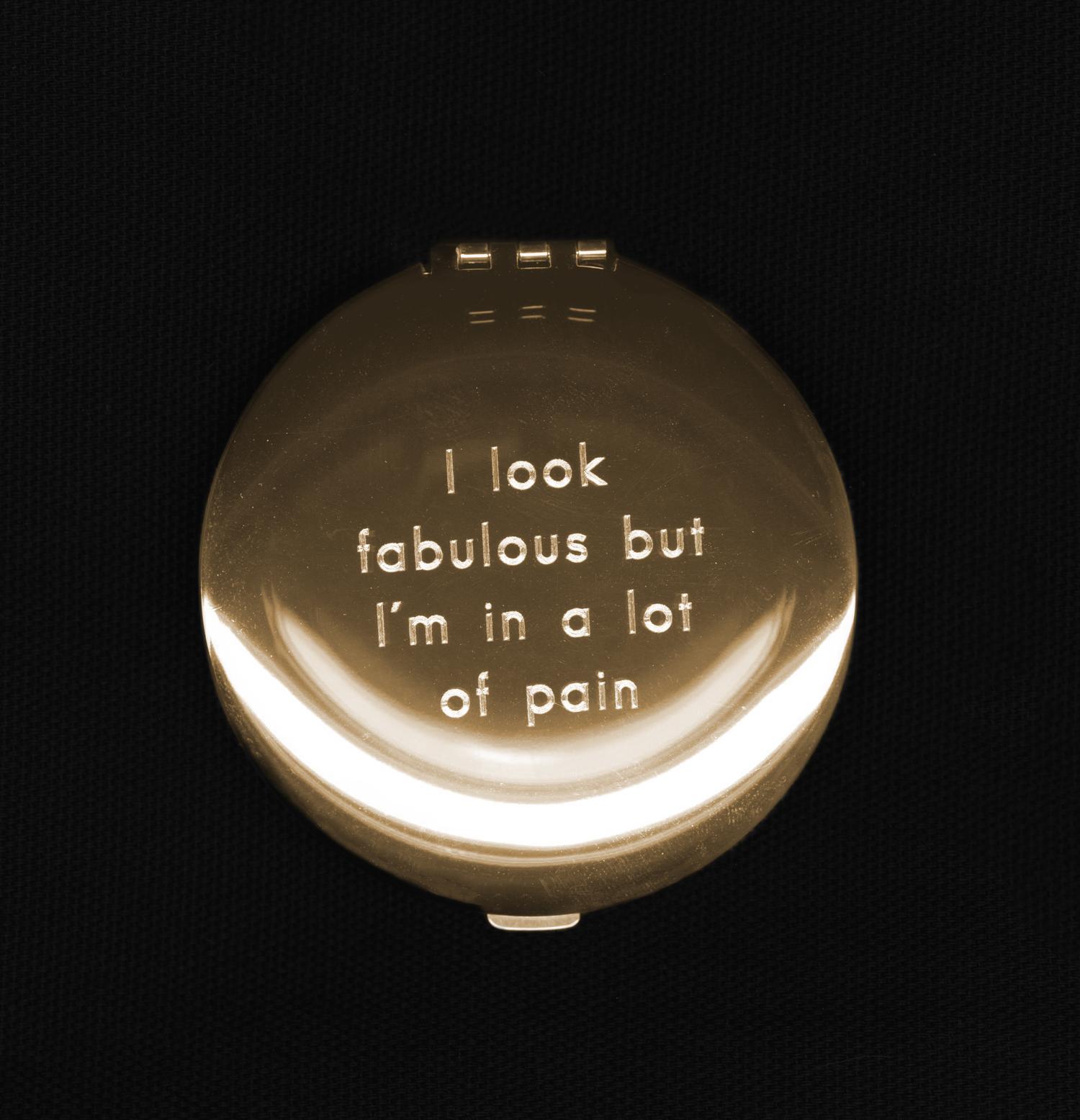 A gold compact mirror is etched to reveal the phrase, “I look fabulous but I’m in a lot of pain”