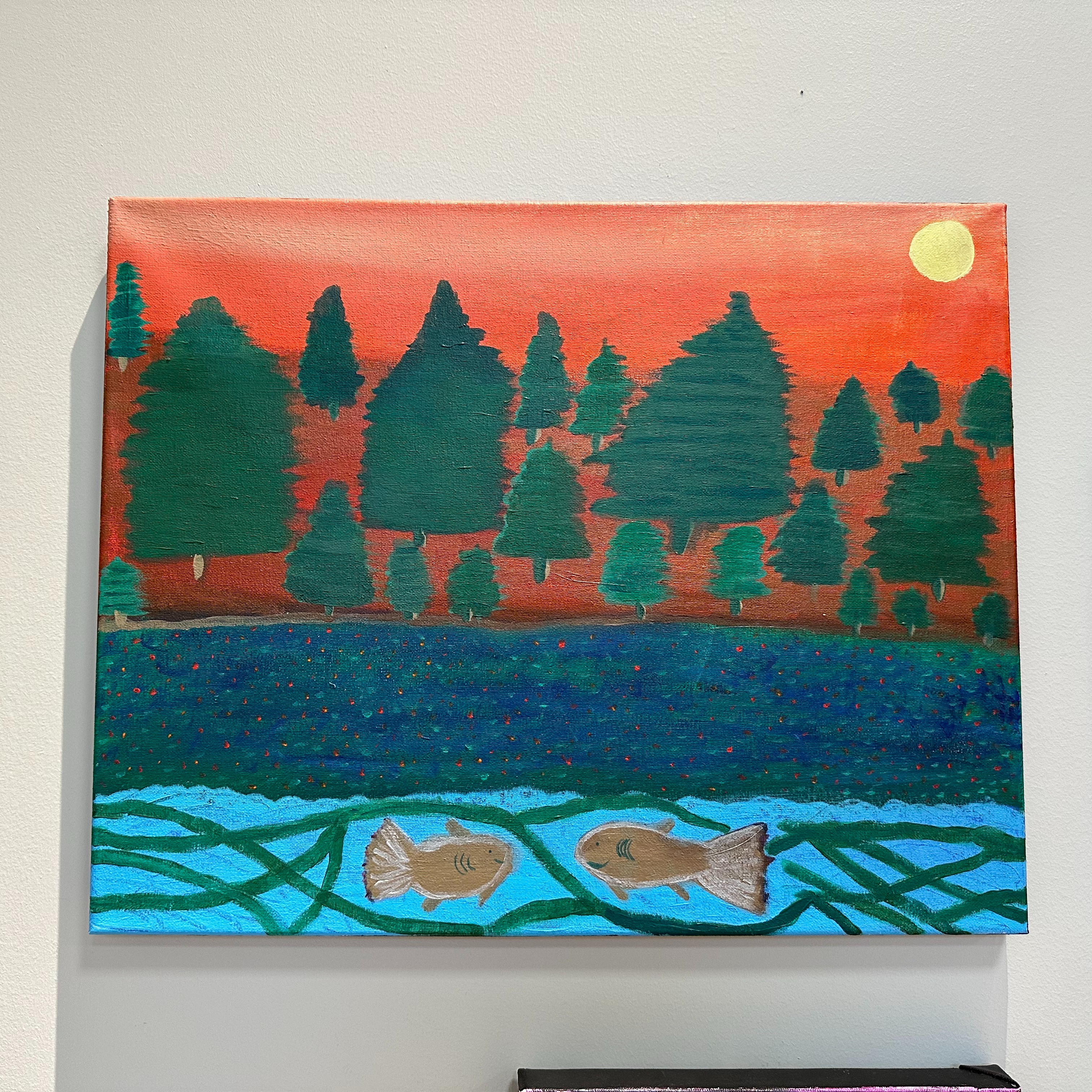 Two silver fish swim facing each other in blue water in the foreground. Green fir trees are in the background with an orange sunset. 