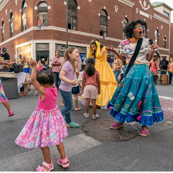 Stage actors dressed as Disney princesses dancing with children in the streets outside of the Zeiterion Theatre
