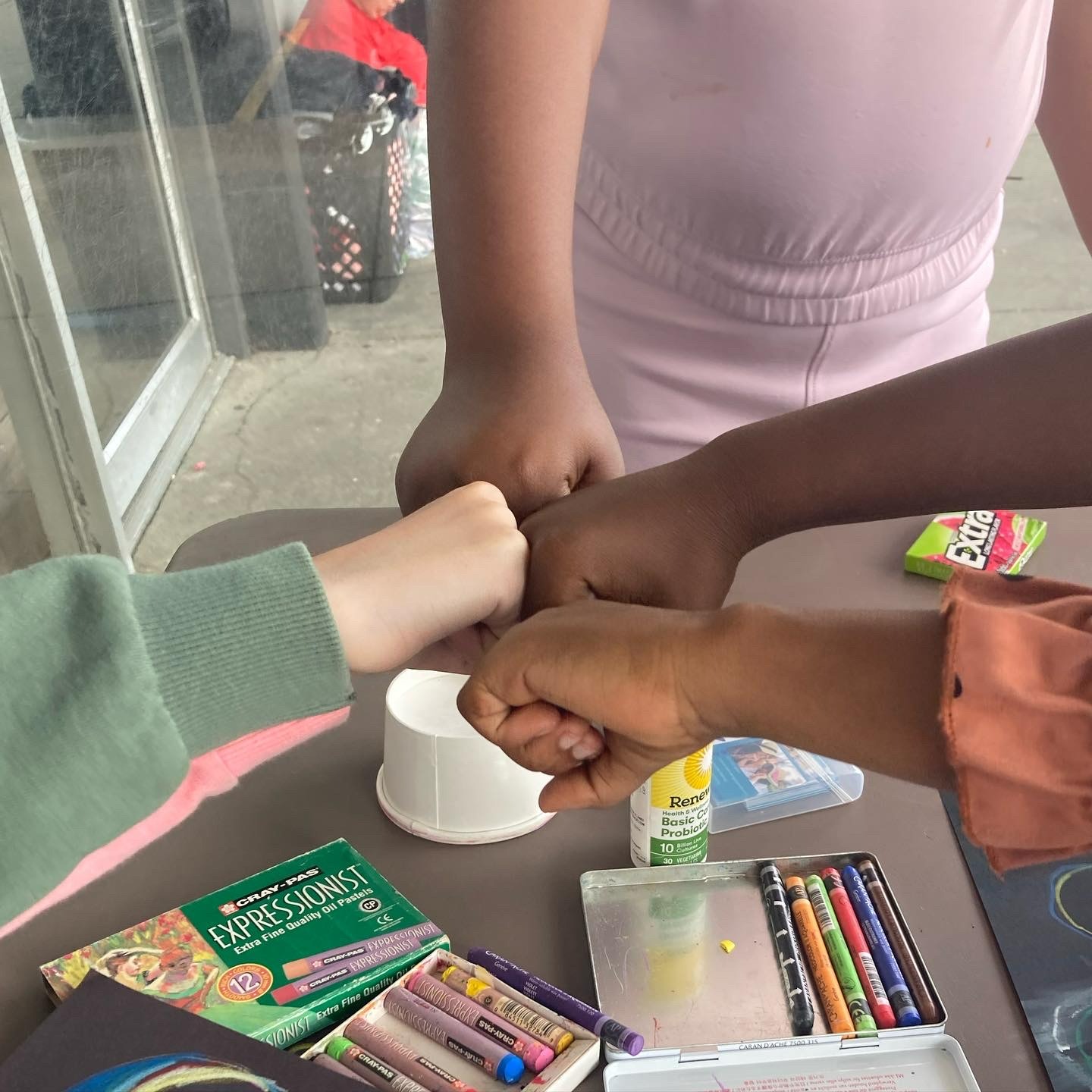 four children fist bump over their artwork