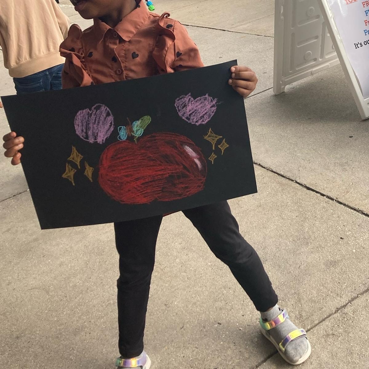 child holds colorful art done on black paper