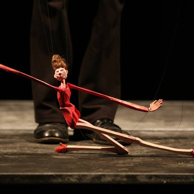 A long limbed ballerina. A wooden marionette in red with stunning heals