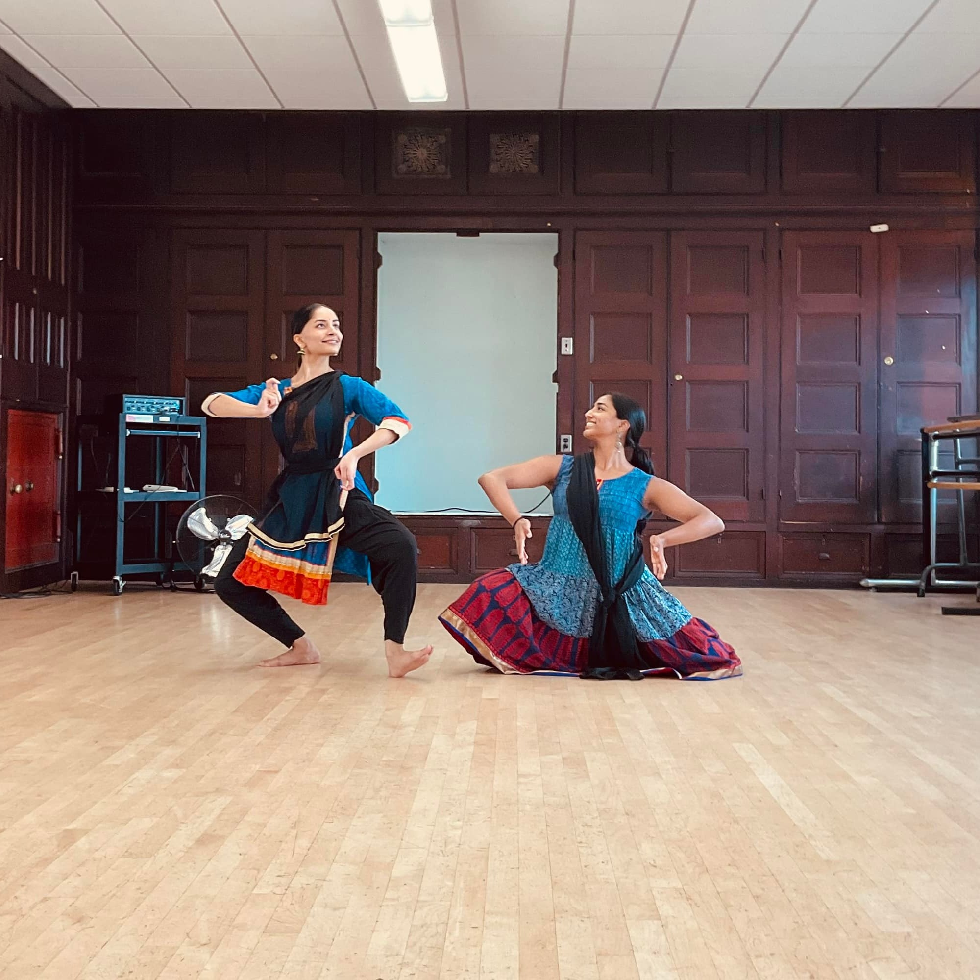 Two women wearing blue and red outfits in dance pose