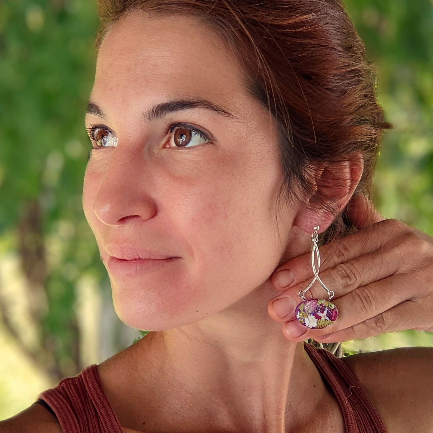 Head shot of the artist, wearing the jewelry she made with dried flowers casted in resin