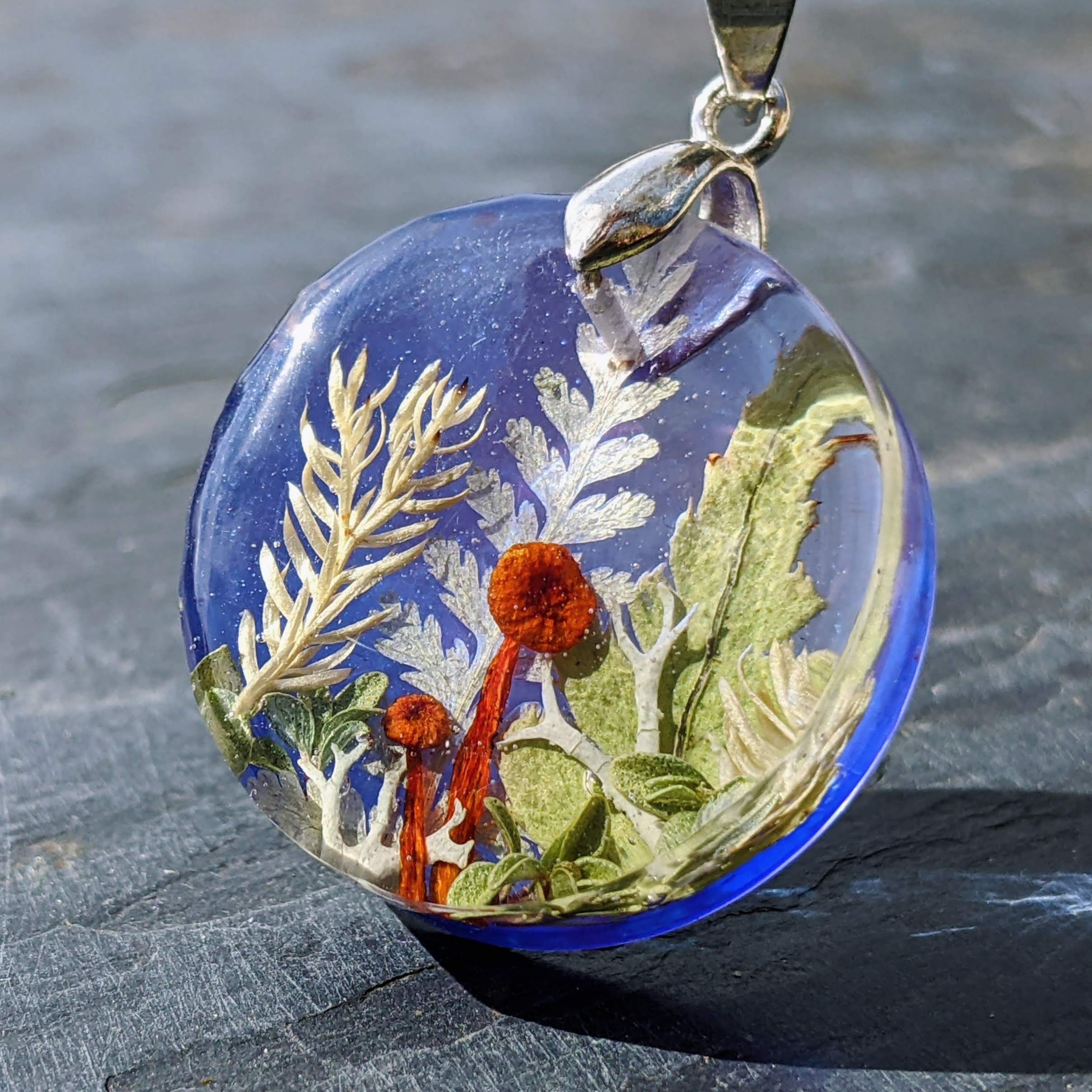 round necklace with Bright red mushrooms casted in blue resin