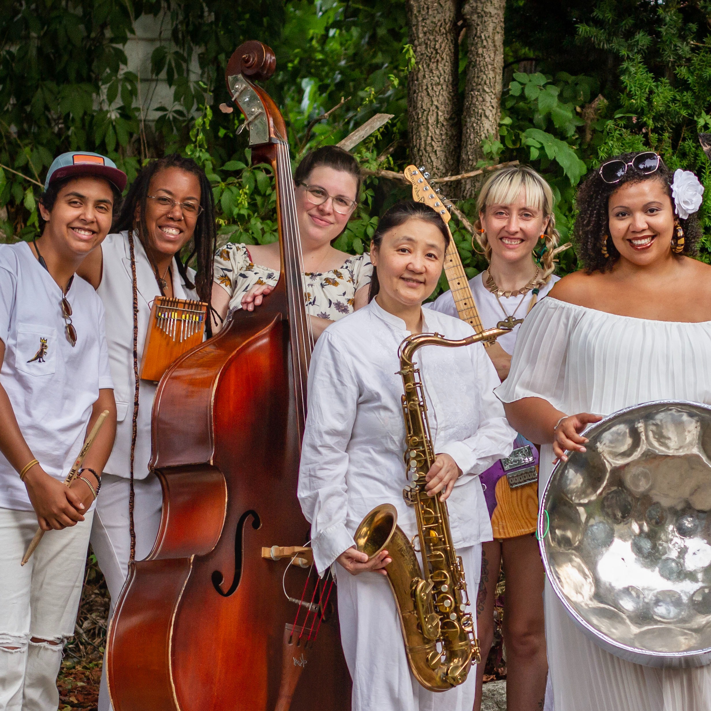 6 members of Zili Misik, holding instruments and smiling, in front of trees 