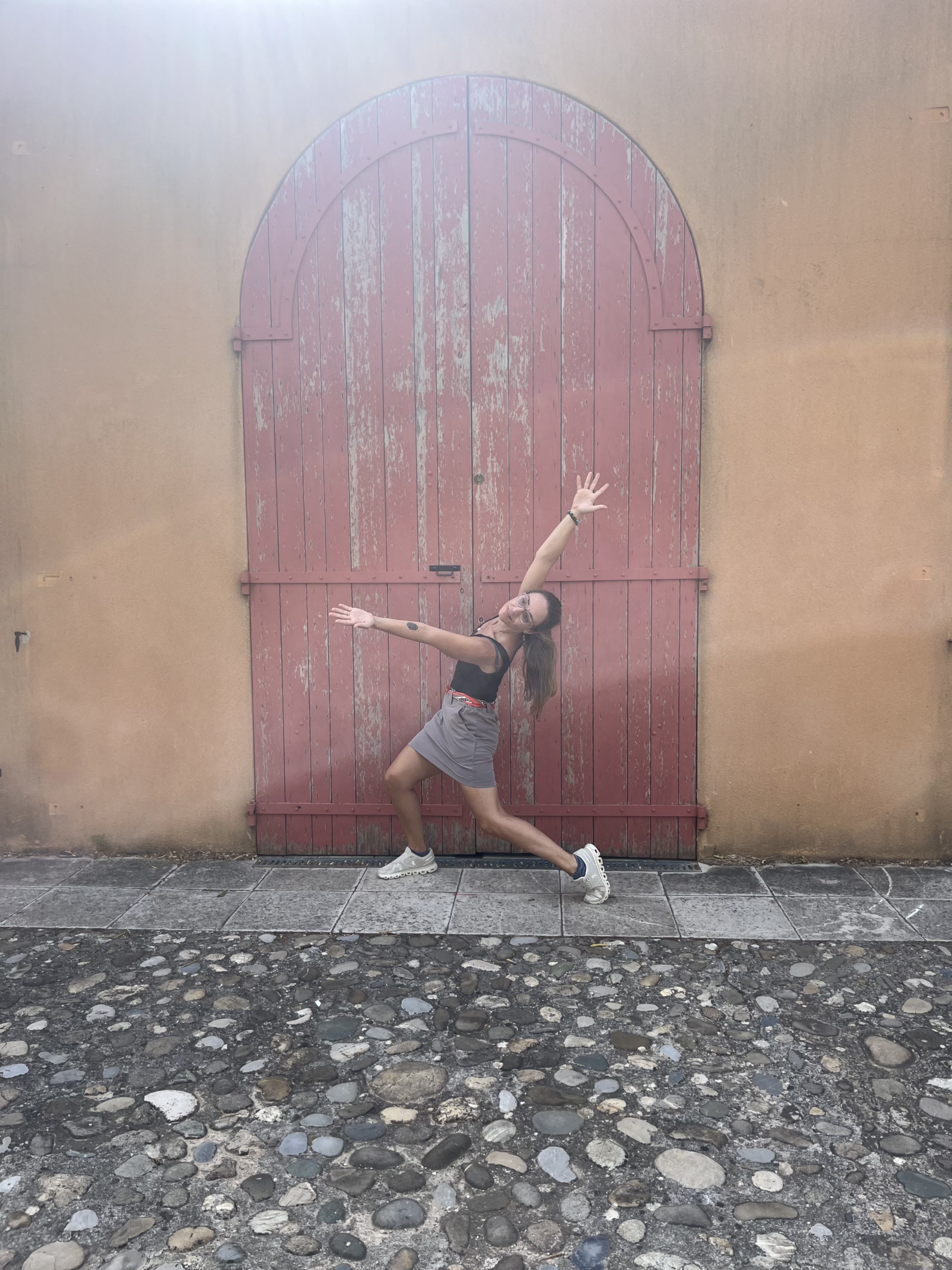 Dancer (Linalynn Schmelzer) making an angular shape with her body in front of a big red door.