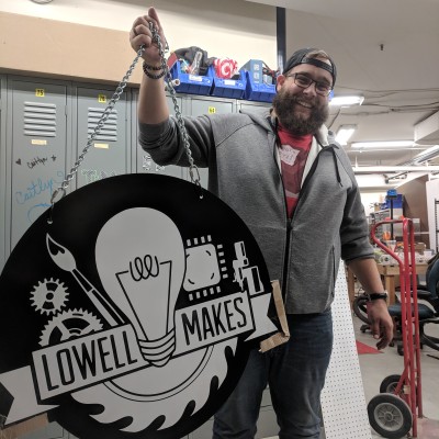 Ben holds aloft the sign which adorned the facade of Lowell Makes' original location.