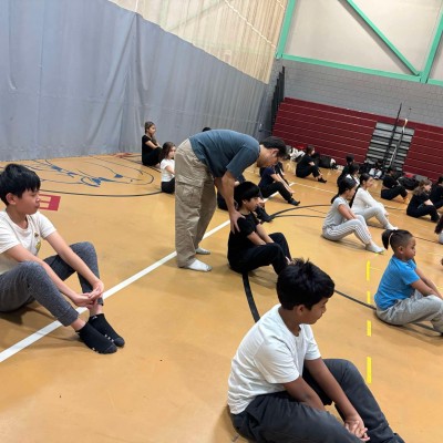 Angkor Dance Troupe instructors teaching Butler Middle School residency students basic dance stretching techniques.